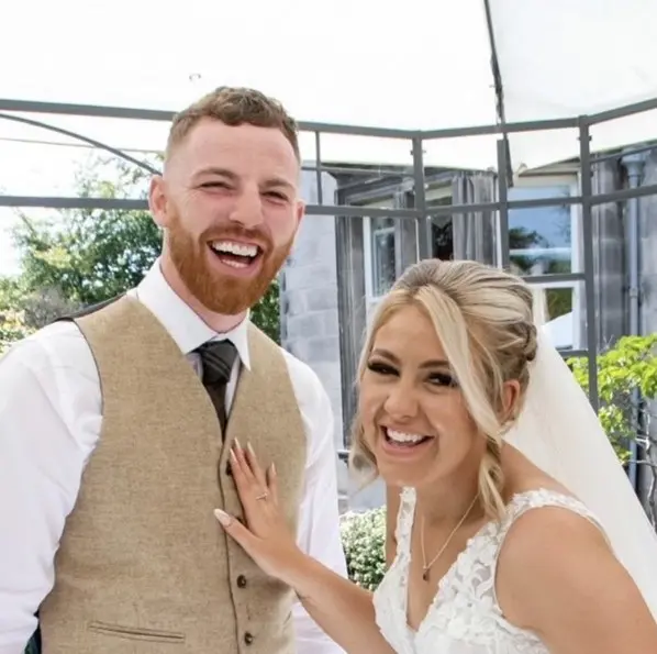 image of a couple at their wedding smilling on a sunny day