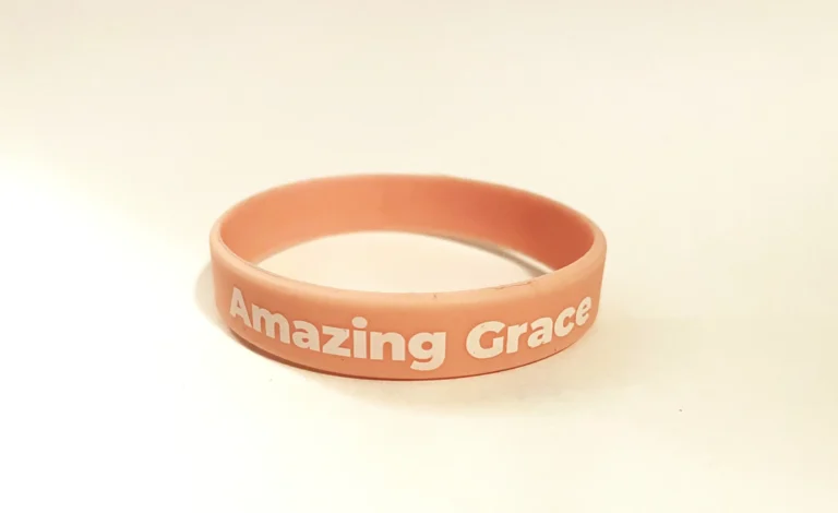 Soft pink silicone Amazing Grace charity wristband in black with printed lettering