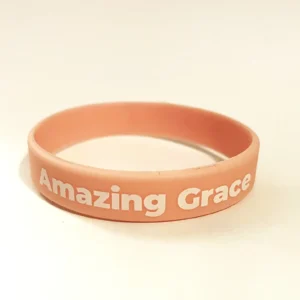 Soft pink silicone Amazing Grace charity wristband in black with printed lettering